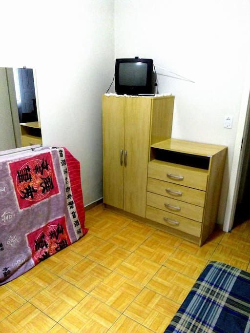 Um mini-roupeiro com gavetas e uma TV pequena.