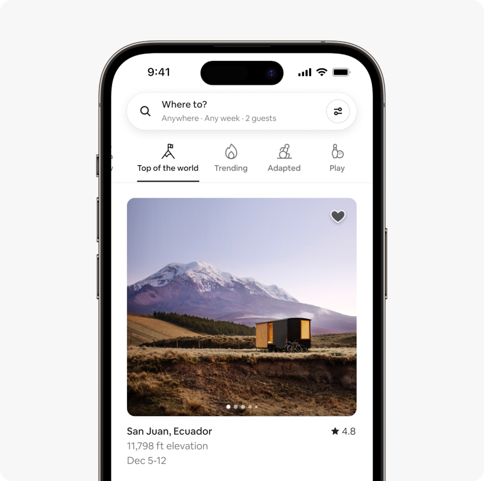 A laptop and a phone show the Airbnb homepage with two rows of homes from a new Airbnb Winter Release category called Top of the World, which features homes at high altitude,around 10,000 feet above sea level.