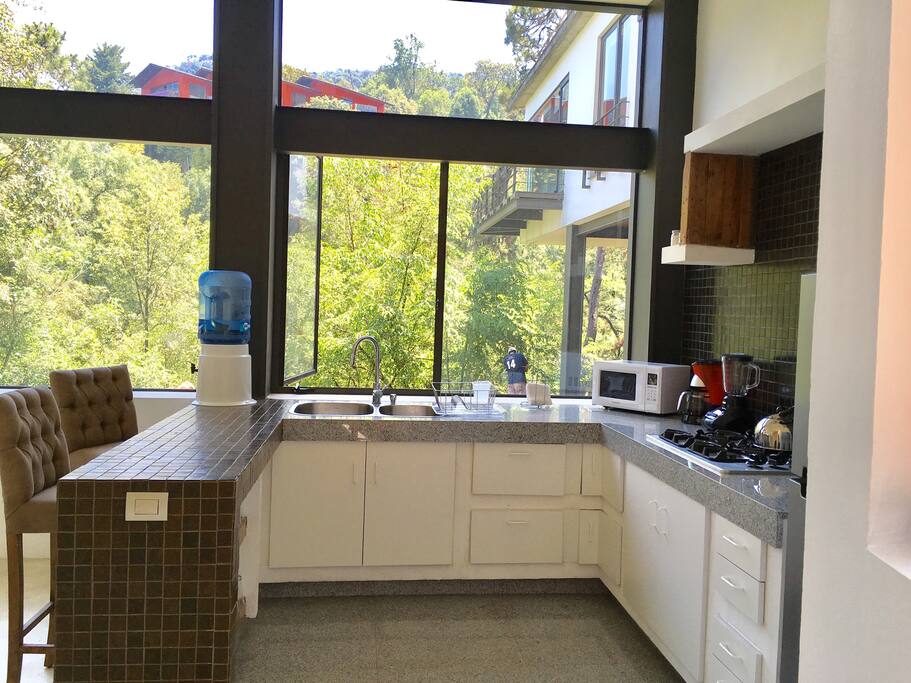Cocina totalmente equipada, con vista al jardín y alberca y cascada.