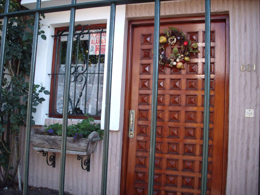 Puerta de entrada principal de la.casa, con rejas y jardín al frente