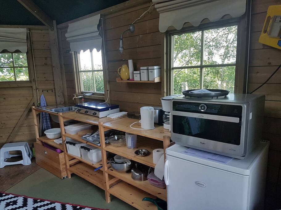 Keuken met stromend water, fornuis, magnetron, oven, grill.
