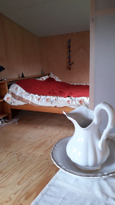 Dit is het slaapgedeelte met een tweepersoonsbed.Een lampetkan waarmee men zich kan wassen.