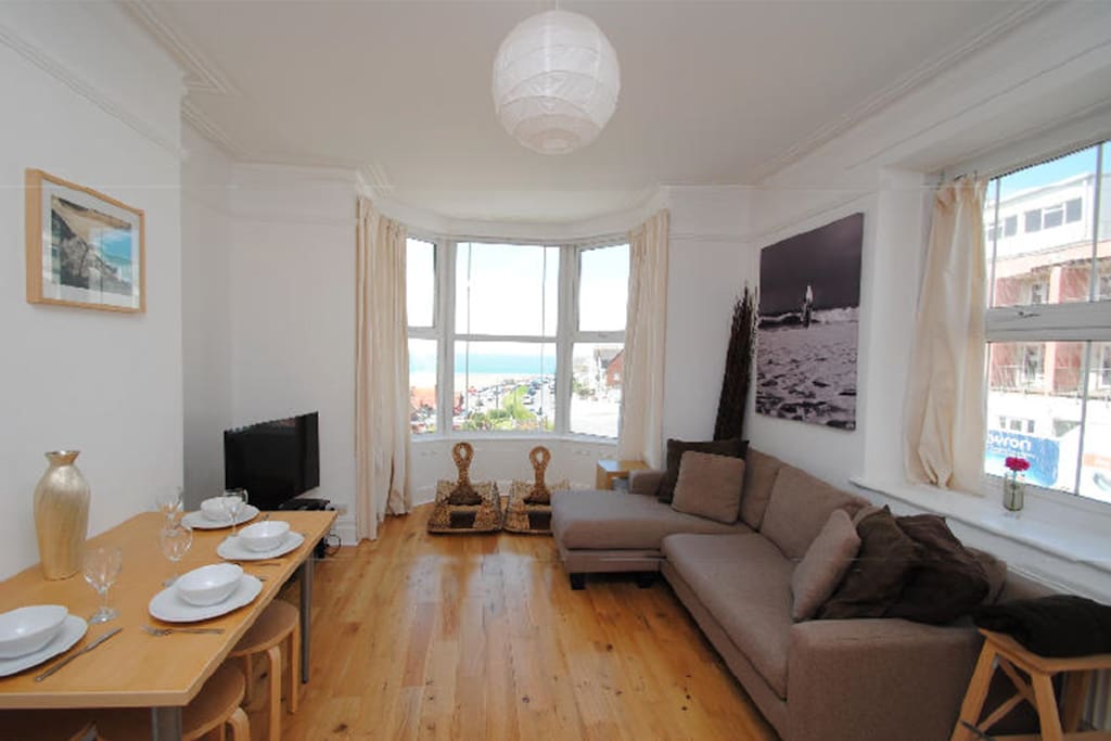 Lounge showing spacious open plan living room with large plasma, bay window and panoramic view of the sea and sunsets.