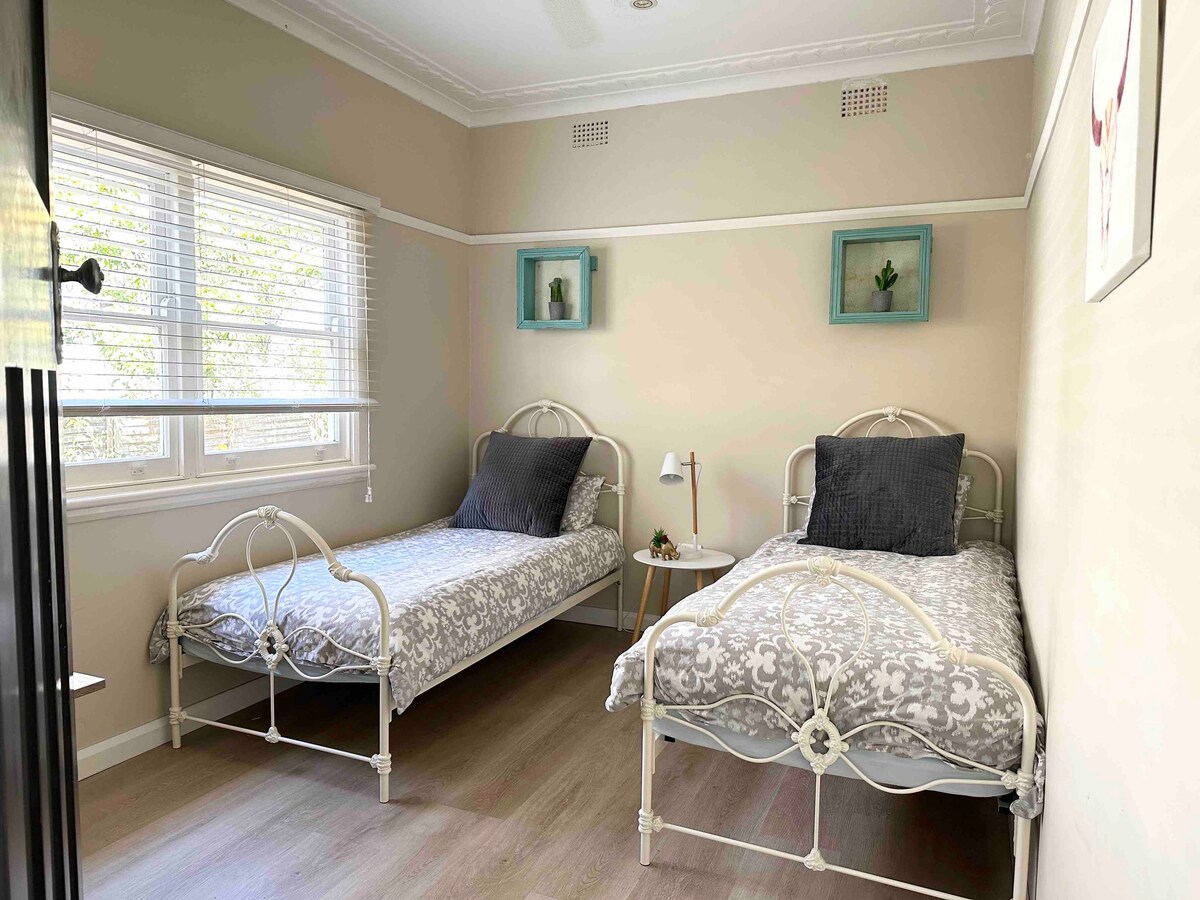 第二间卧室配有2张单人床、吊扇和1张书桌。