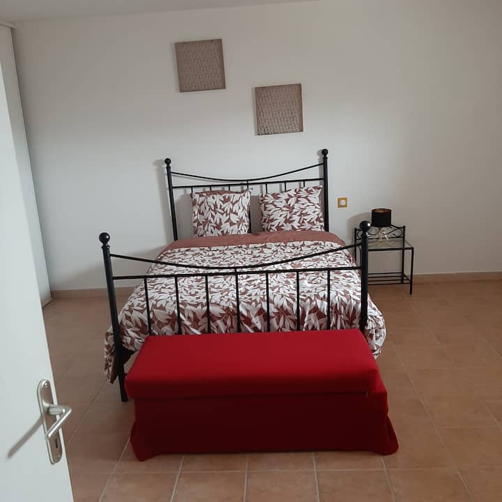 Ambiente cálido y luminoso para esta habitación acogedora con su banco rojo al final de la cama, perfecto para leer, colocar su maleta o simplemente relajarse.