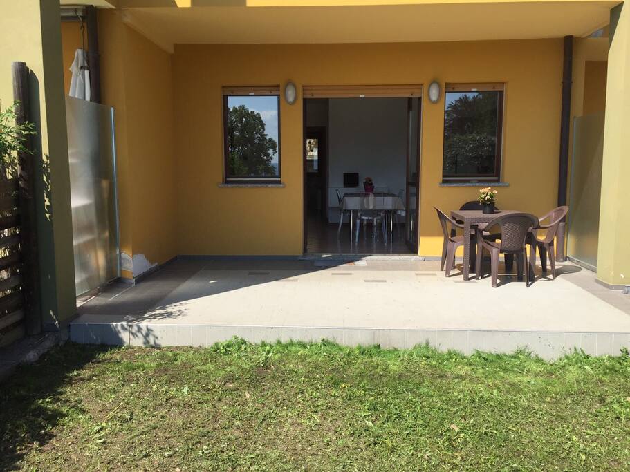 Terrazzo coperto con giardino, tavolo, sedie e sdraio