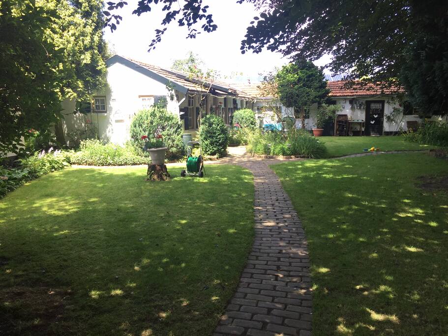 Privé pad naar het huisje, gelegen in een grote tuin met veel bomen en een zwembad.