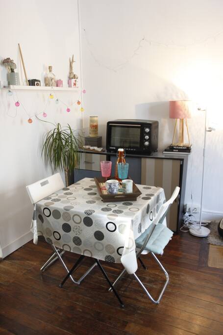 Le coin repas avec une table pour 2 personnes et un four électrique.