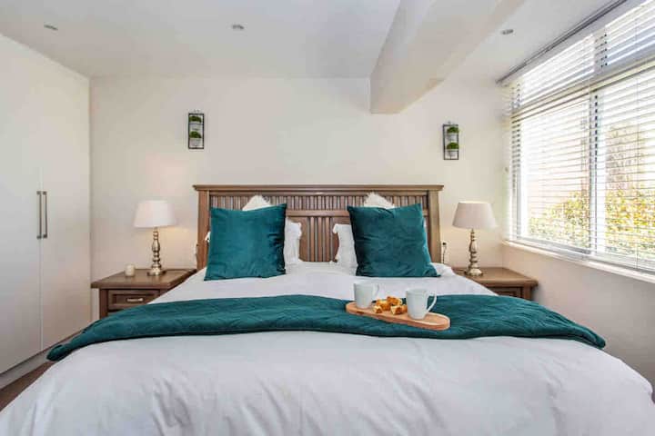 Dormitorio principal con cama tamaño king, televisor inteligente de pantalla plana y estación de trabajo. 