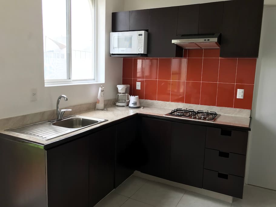 Cocina integral equipada con microondas, licuadora, vasos, platos, cubiertos, etc.