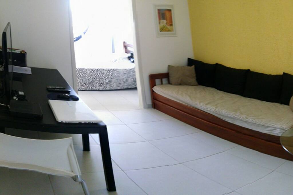 Sala com bicama de solteiro que também é o sofá, mesa alta com banqueta e mesa grande com 2 cadeiras. TV 46" com NET e WiFi