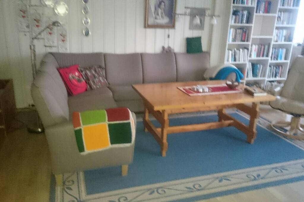 Stue med hjørnesofa og to spisebord.