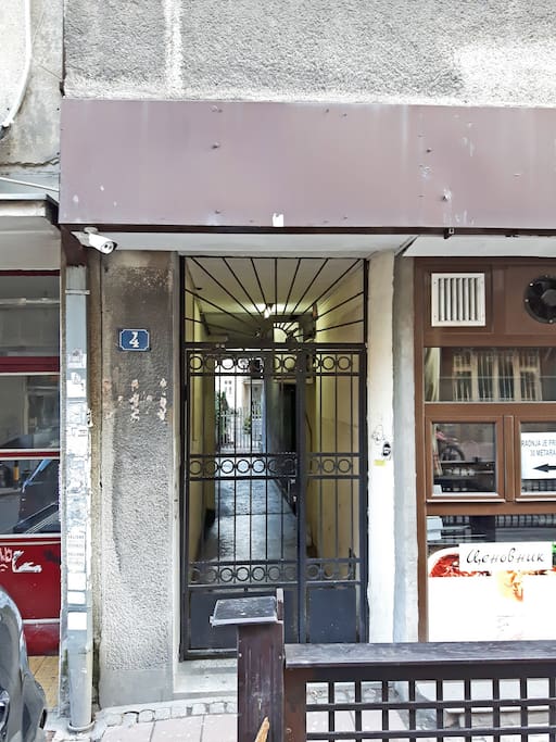 The gate of the building. The entrance to the building is on the right, after the gate