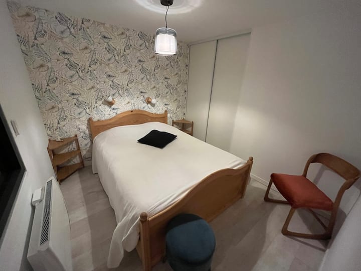 Chambre avec lit double de largeur 140 cm, équipée de volets roulants électriques et placard de rangement.