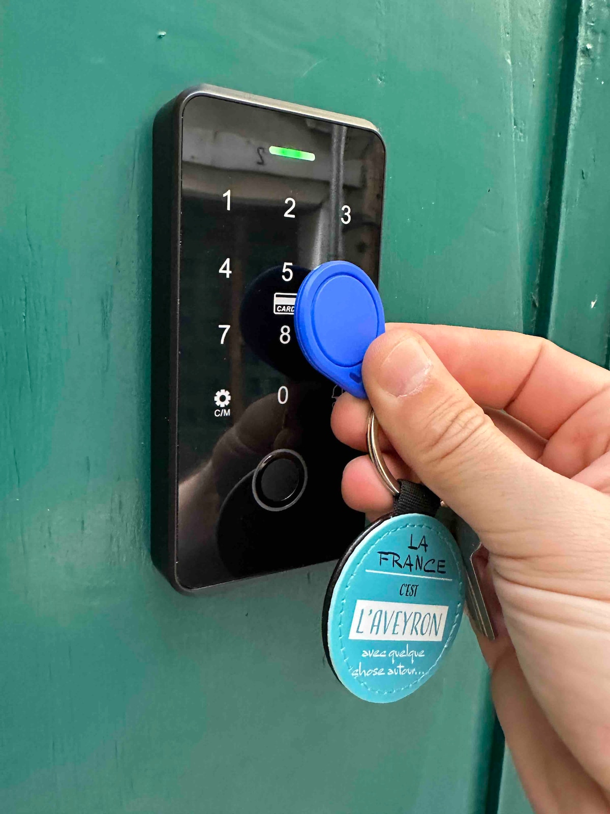 A close-up view of a modern keyless entry system is shown, featuring a digital keypad alongside a key fob being presented for access. The door's vibrant green color provides a contrasting background, emphasizing both functionality and security.