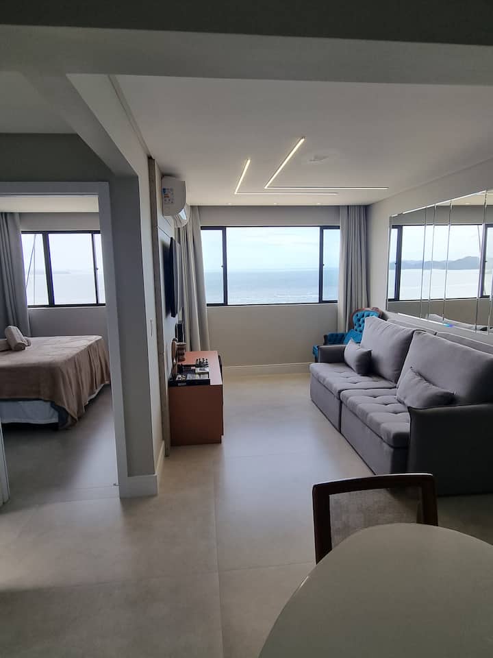 Поглед кон кујната, гледајќи го морето низ дневната соба и кварцниот апартман во спалната соба.