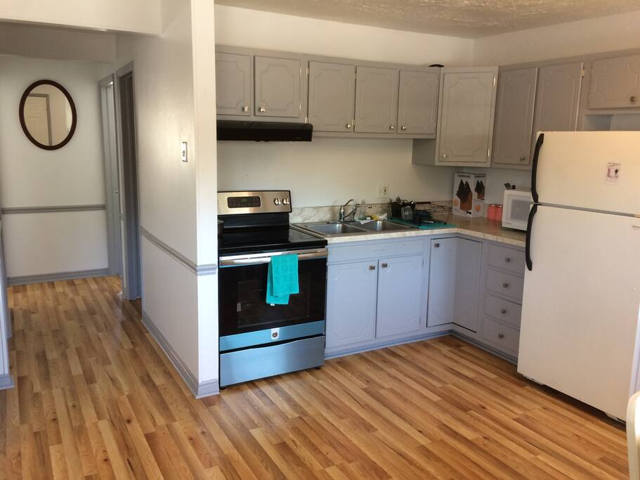 Kitchen with brand new stove, equipped with dishes and silverware, pots and pans