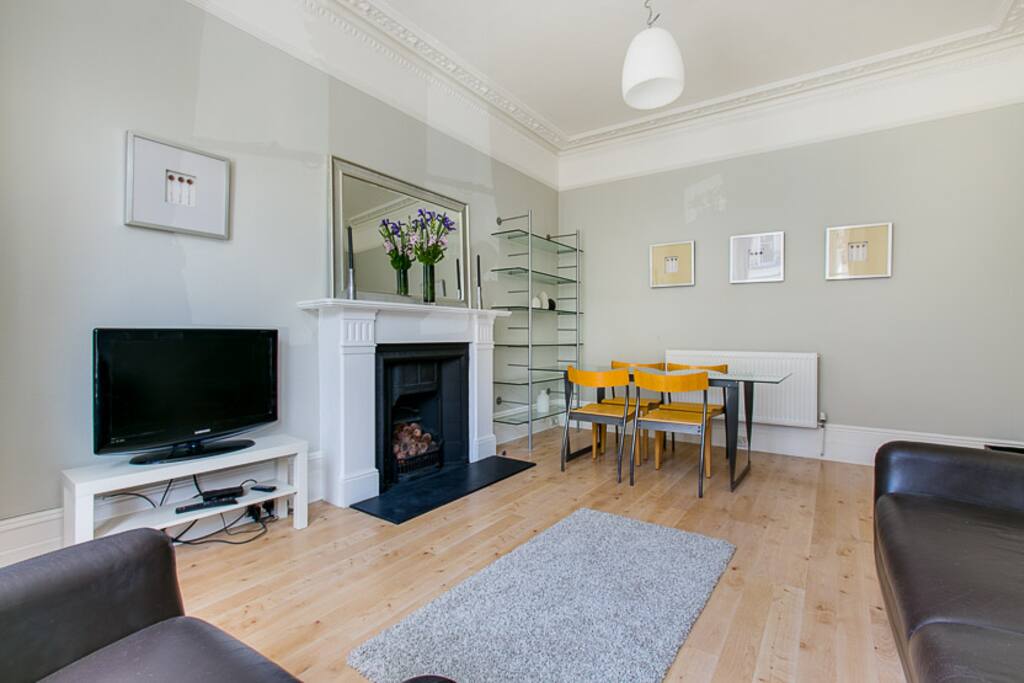 large sitting room with double sofa bed, dining table for 4 and TV