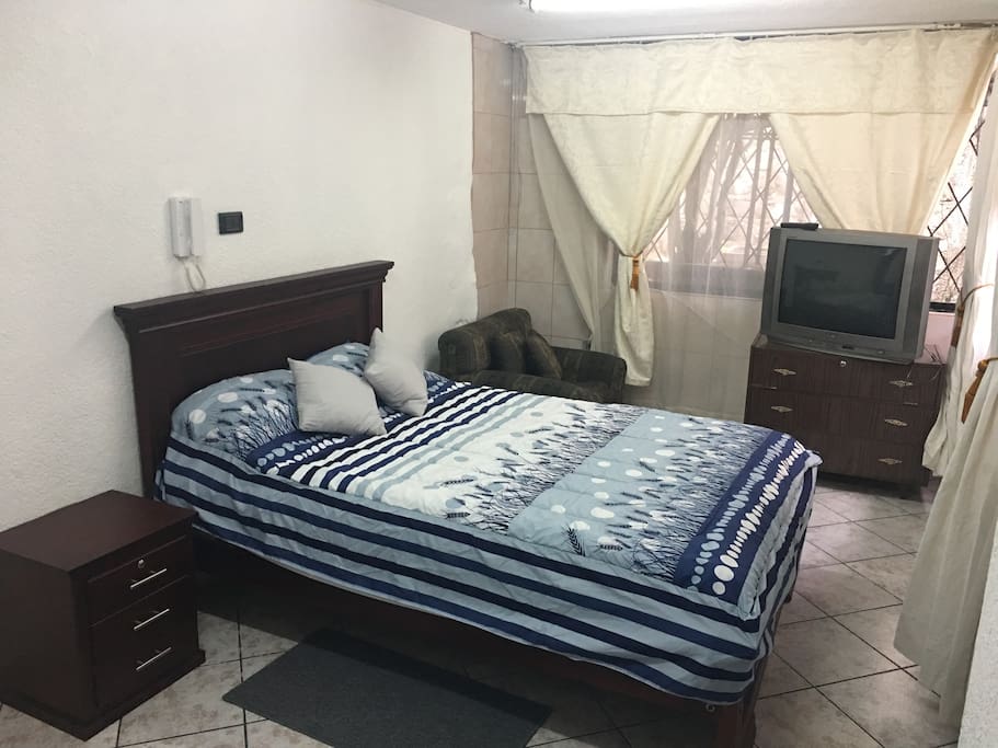 cama con velador, cajonera y televisión