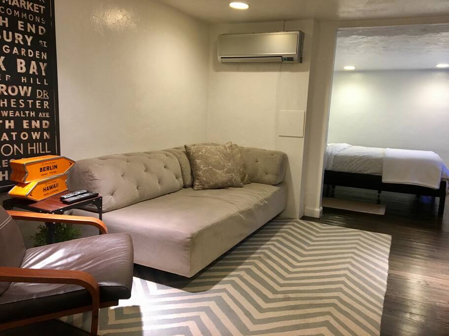 Big couch in living room, open to bedroom.