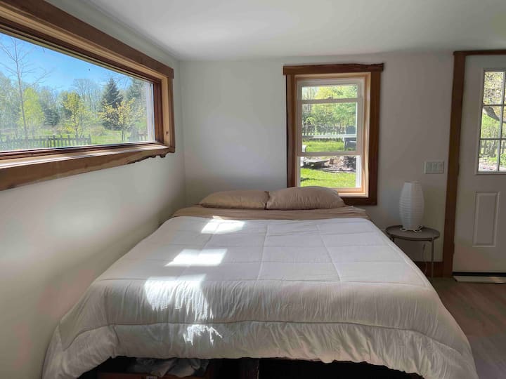 The comfy queen-size bed downstairs in an open floor plan. The downstairs is set up like a studio apartment, open to the living space and kitchen. 