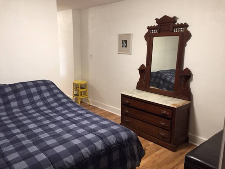 Queen size bed with dresser, closet and storage bench in bedroom.