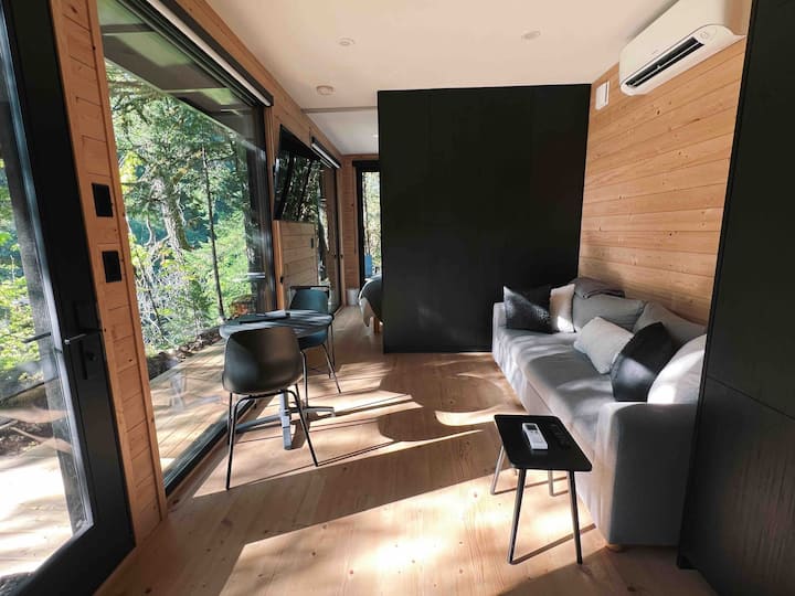 The living space features wall to ceiling windows, AC, and a sliding door to close off the bedroom. The sofa is also a pullout bed and the TV swings from the living room into the bedroom. 