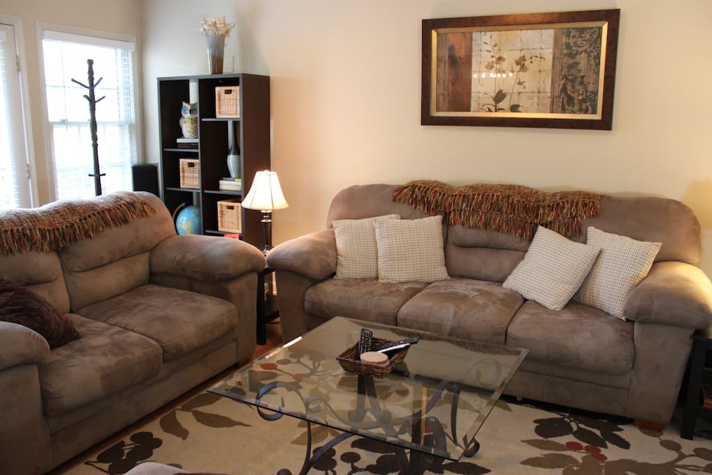 Living room, entrance located behind couch next to window seen here