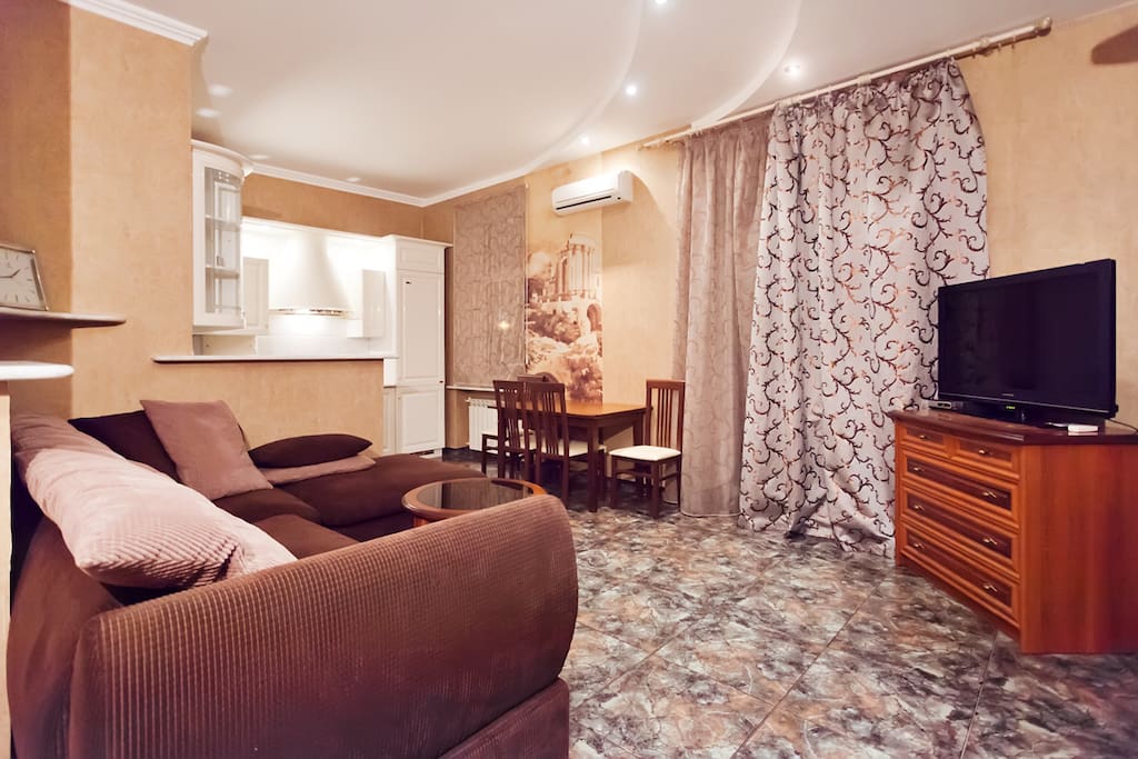 A living room with kitchen area - studio. large corner sofa-bed, air conditioning, large screen TV, a dinner table and 4 chairs. The kitchen is fully equipped with all the dishes.