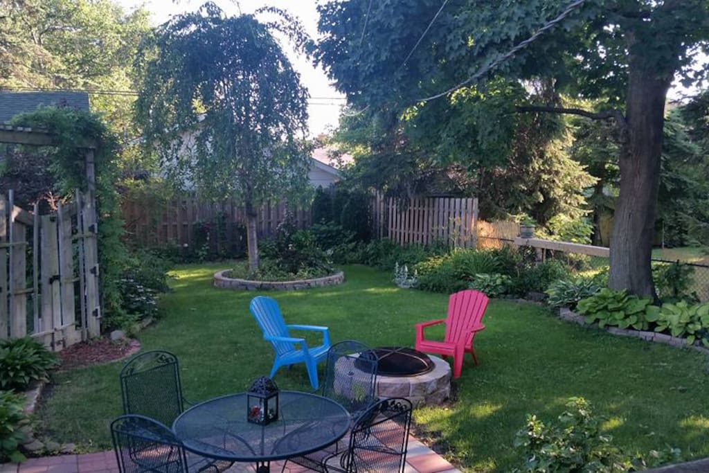 Beautifully landscaped back yard with perennial gardens and fire pit