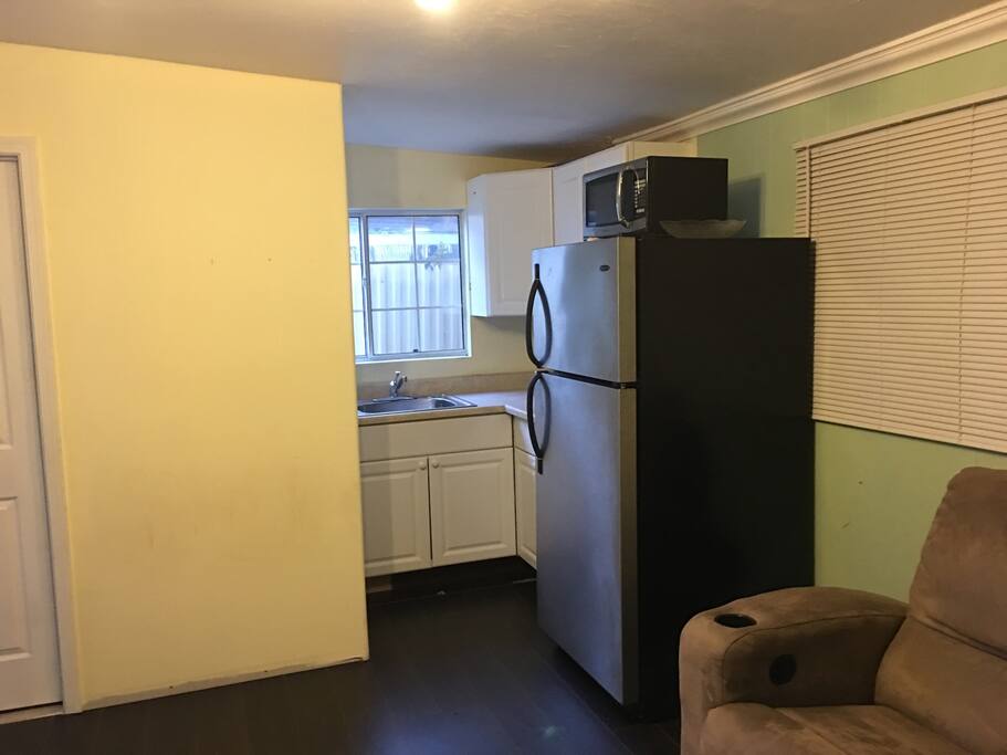 Kitchen area including microwave oven small portable cooktop and full size refrigerator.