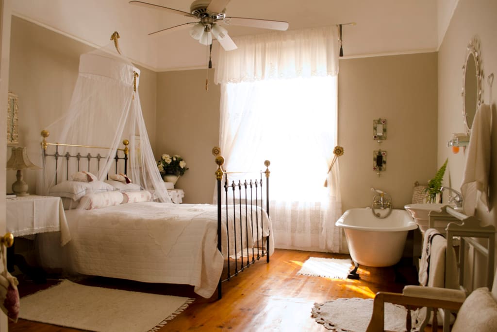 A classic style room with double bed, and a vintage bath tub in the room.