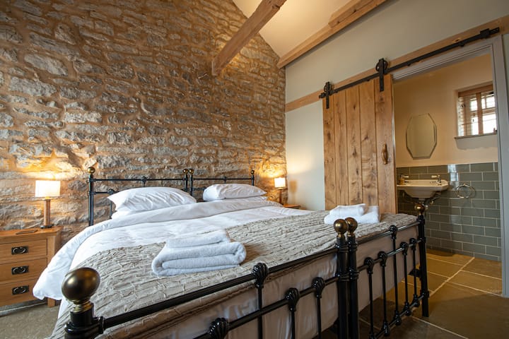 Dormitorio con piedra y vigas originales.