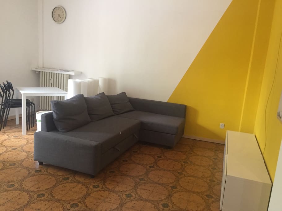 Soggiorno con divano letto per due persone e tavolo da pranzo