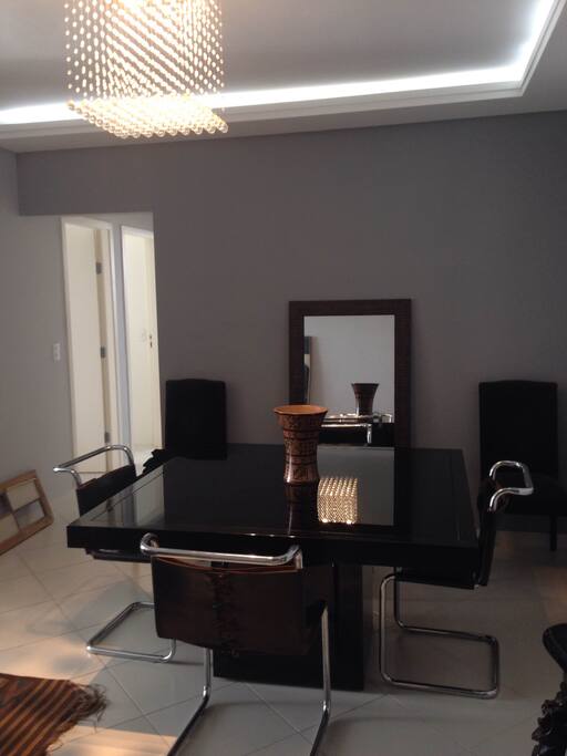 Sala de jantar com mesa em laca e tampo de vidro e cadeiras de couro.