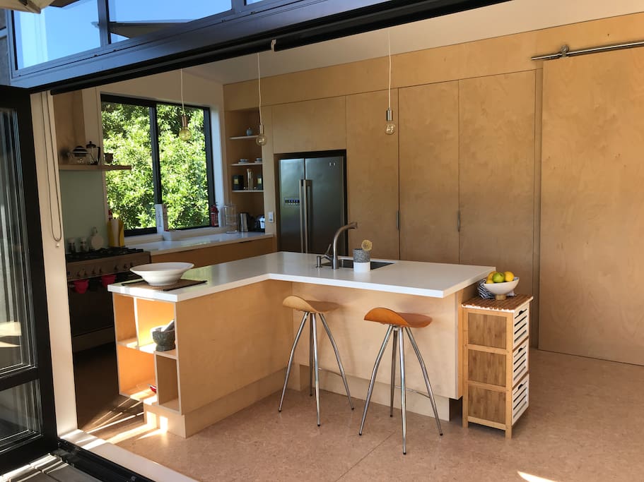 Modern fully equipped kitchen with gas hob leading onto deck with outside seating and umbrella.