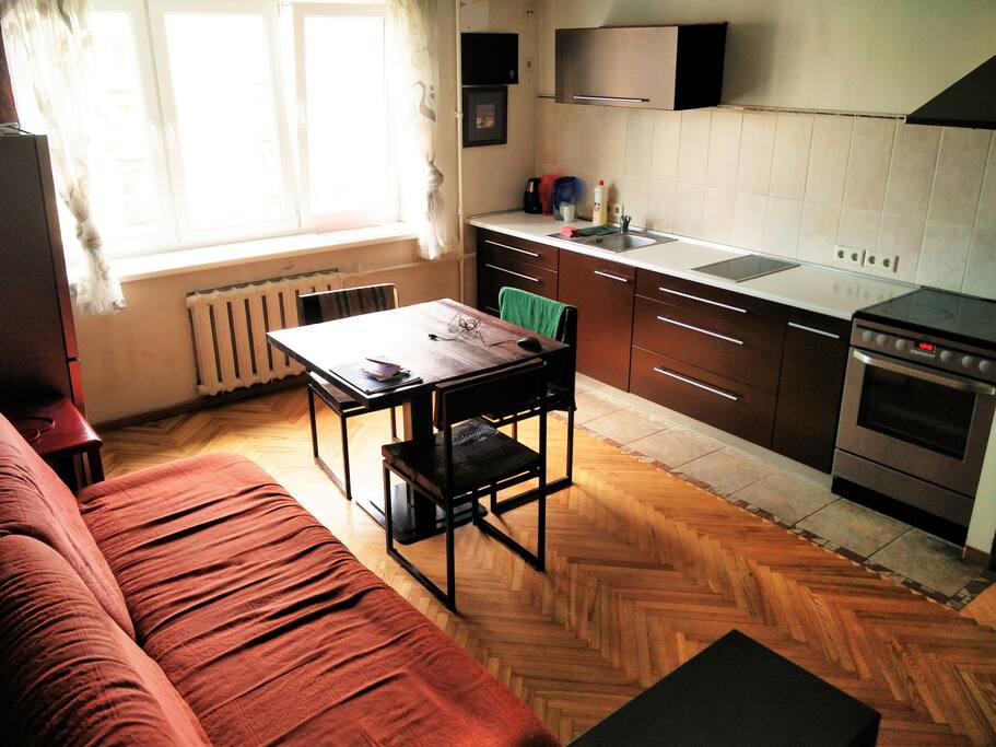 The living room area with the fridge, sofa and kitchen area