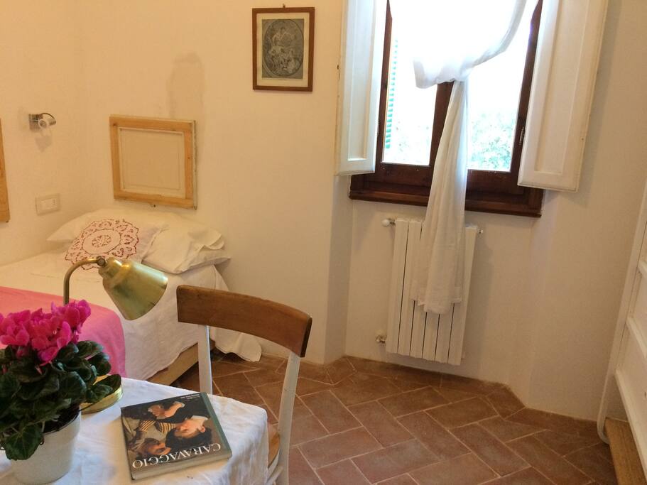 The cozy bedroom has all the essentials, a single bed (with a second pull out bed under), a small desk and chair, an organizer for personal belongings and a window facing the neighbor's secret garden.
