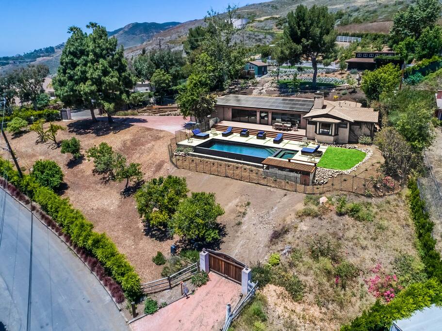 A view of our front yard showing some orange trees in front of the pool, our amazing back yard as well as some of the mountains in the background. The orange trees are full of oranges for you to pick in the summer.