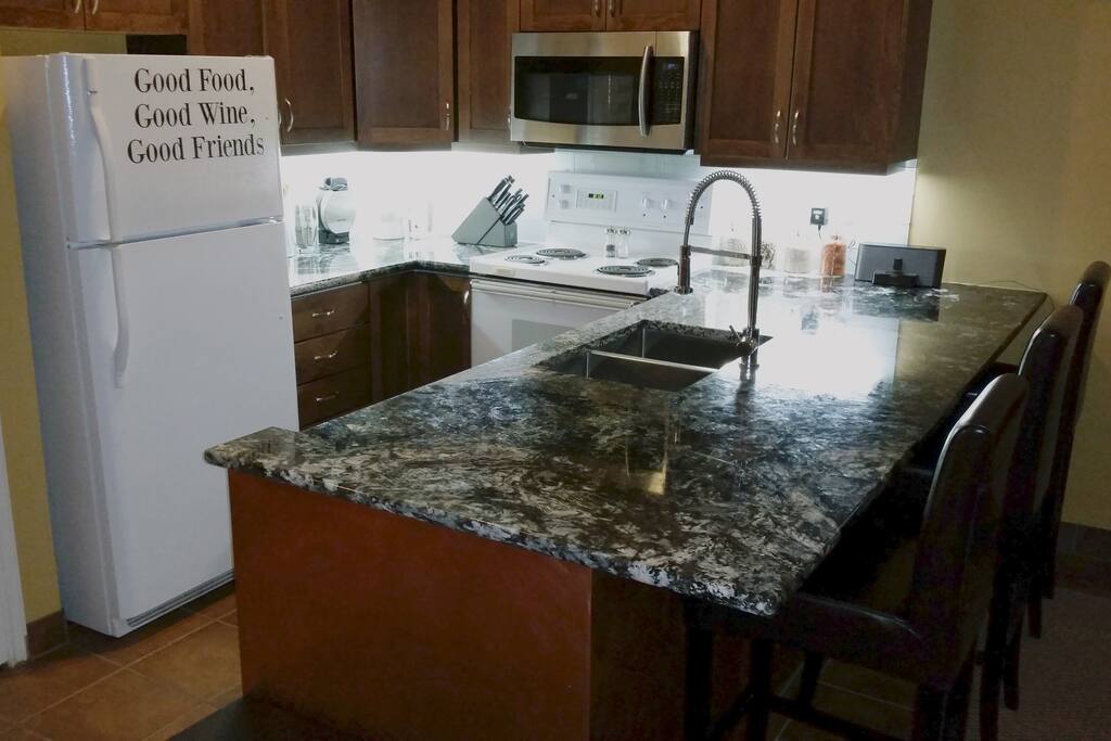 Massive granite counter-top in well lit kitchen. High end cooking equipment so you will feel right at home.