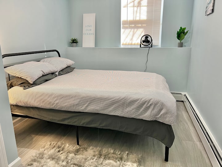 Private bedroom 1, with a queen bed and closet, separated from the rest of apartment by a door.