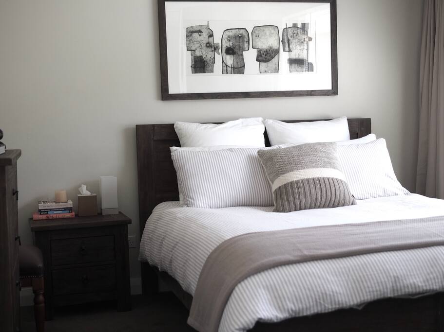 Queen bed with quality linen and sun-drenched in the morning.