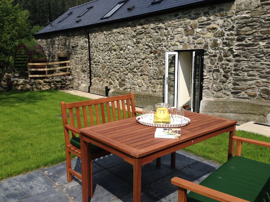 A private enclosed south facing garden with waterwheel and outdoor furniture.