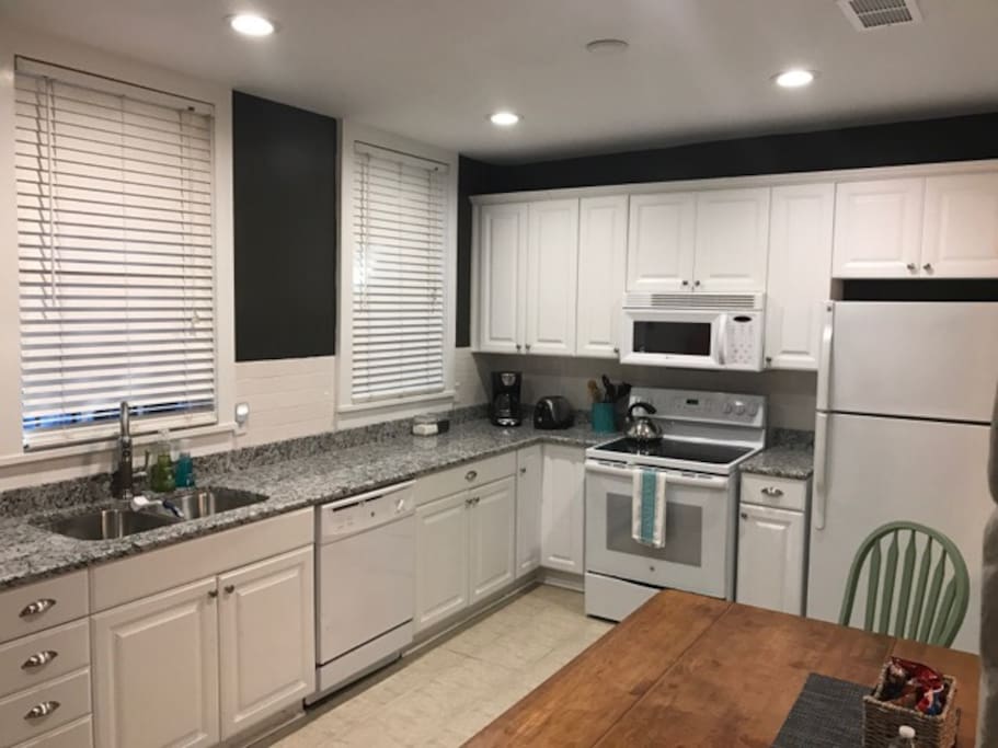 Fully furnished kitchen with granite countertops, cookware, and serving dishes.