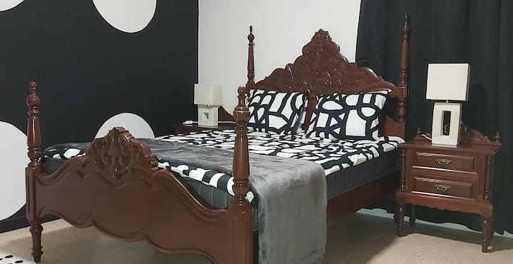 Cama antigua grande y cómoda con colchón nuevo. Tomacorrientes junto a la cama. Luz y ventilador de techo con control remoto. Baño privado dentro de la espaciosa habitación.