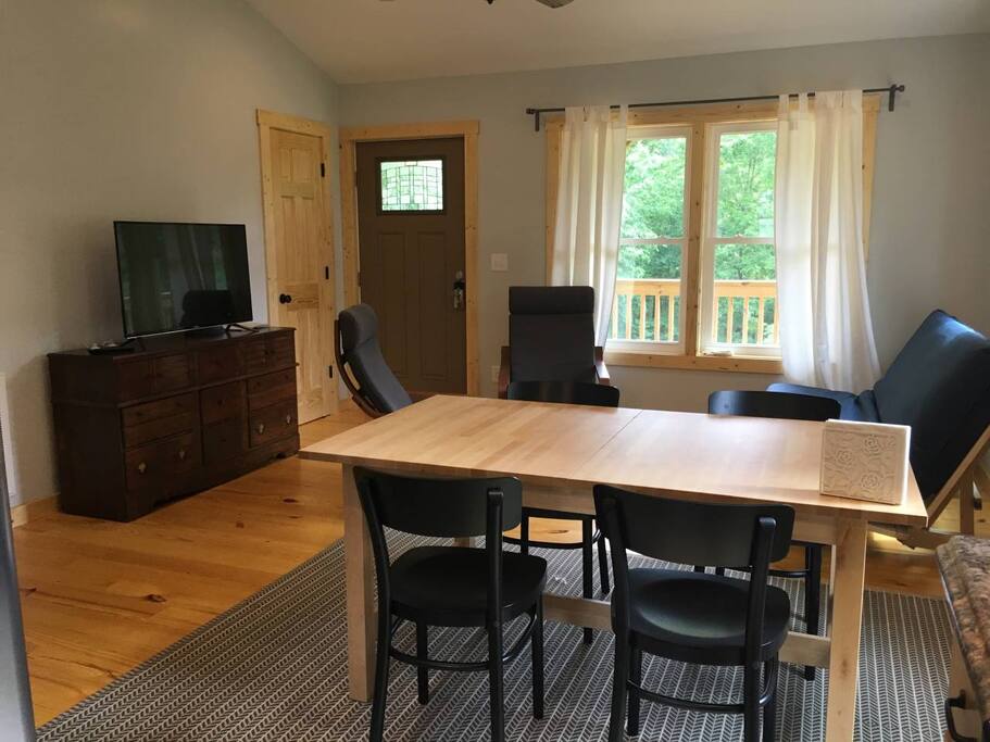 Comfy living room with vaulted ceilings, dining table, futon sofa TV and chairs