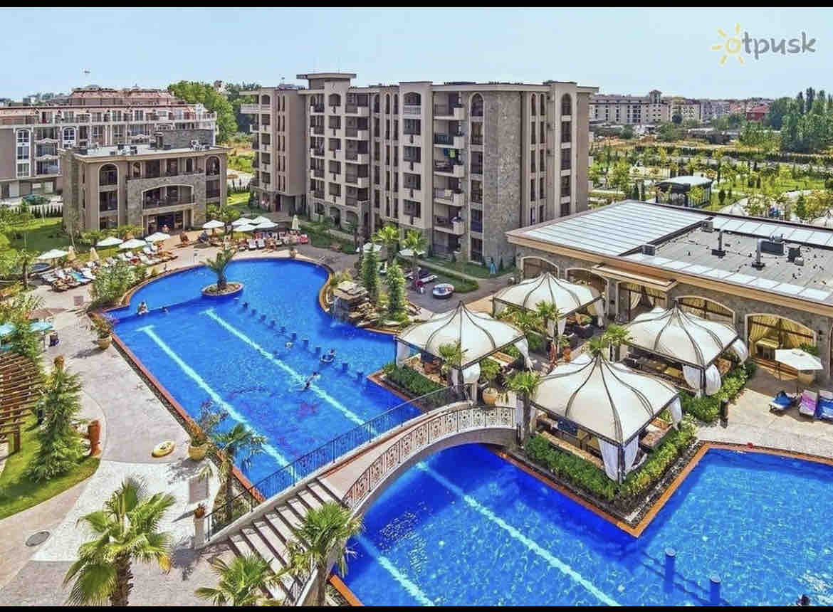 A view of the resort showcases multiple swimming pools surrounded by lush landscaping. Elegant cabanas and lounging areas are positioned near the water. The modern buildings are visible in the background, providing an inviting backdrop to the outdoor leisure space.