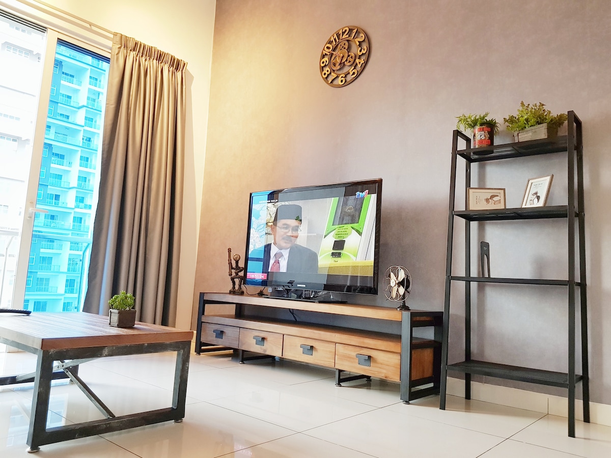 A modern living area is presented with a sleek television on a low wooden media console. Decorative items are arranged on a minimalist black shelving unit. Natural light filters in through large glass doors, while light curtains frame the windows, enhancing the contemporary industrial decor.