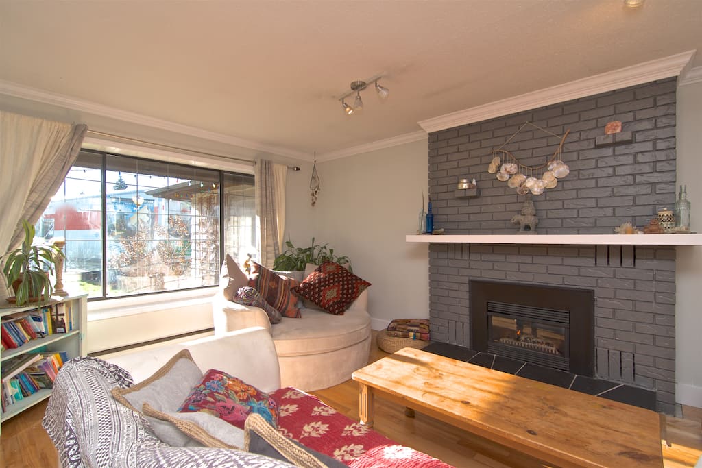 Cozy and open living space with gas fireplace, large comfy round couch perfect for a morning read with a ton of natural light shining through the wall-sized window.