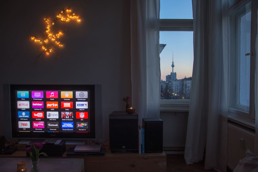 Wohnzimmer: Der ‚Königinnenplatz’ mit Blick auf Fernsehturm, Fernseher (Apple TV mit Netflix, Satellitenempfang, CD/DVD/Blu Ray-Player) und den Kamin // living room: the ‚queen’s seat’: see the tv tower, the tv (with Apple TV, satellite TV, CD/DVD/Blu Ray player) and the fireplace from the comfort of the couch